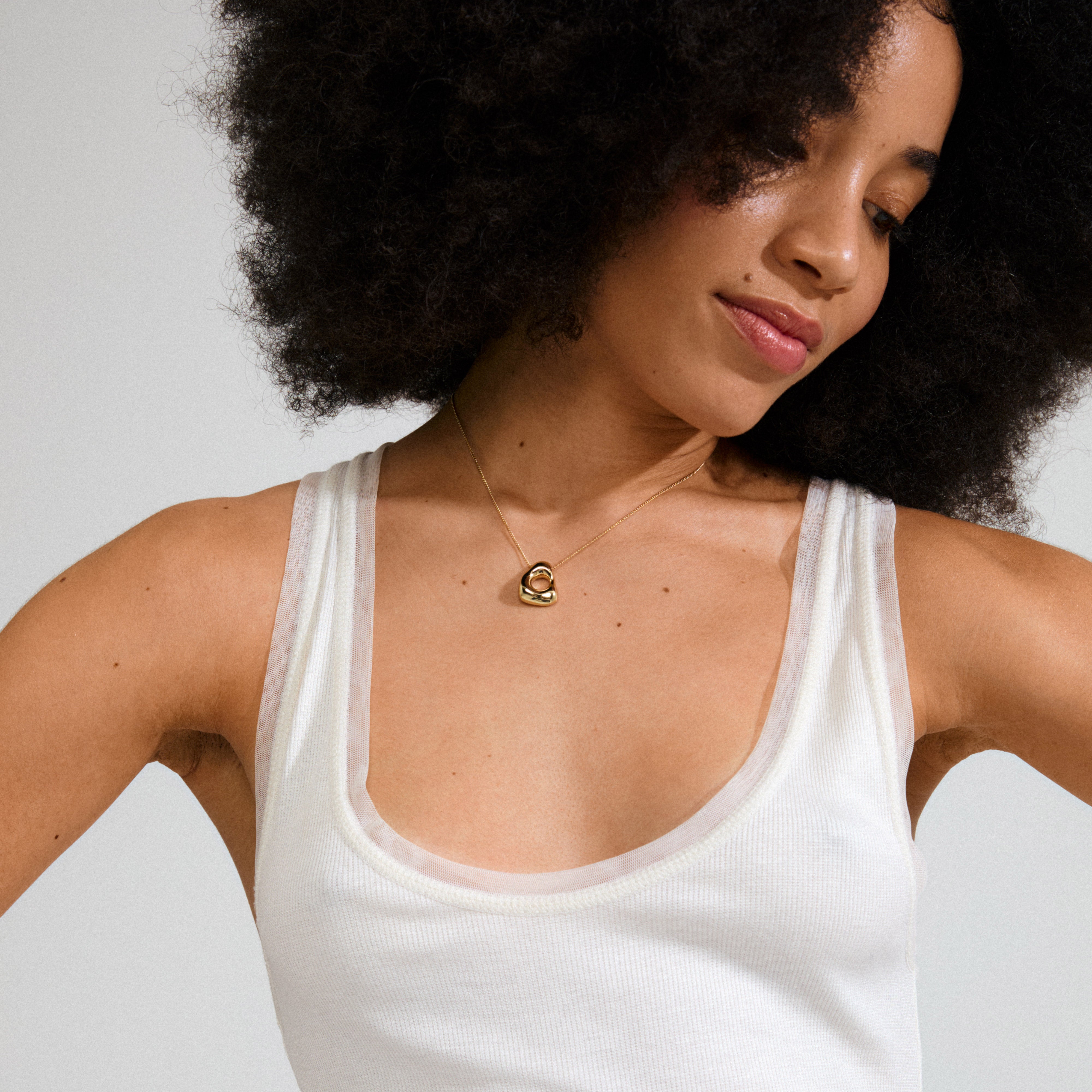 Woman wearing Pilgrim's FREE necklace 168一分钟极速赛车--|实时赛果直播视频 gold-plated, featuring an abstract heart-shaped pendant on a delicate chain, embodying minimalist elegance and natural inspiration.