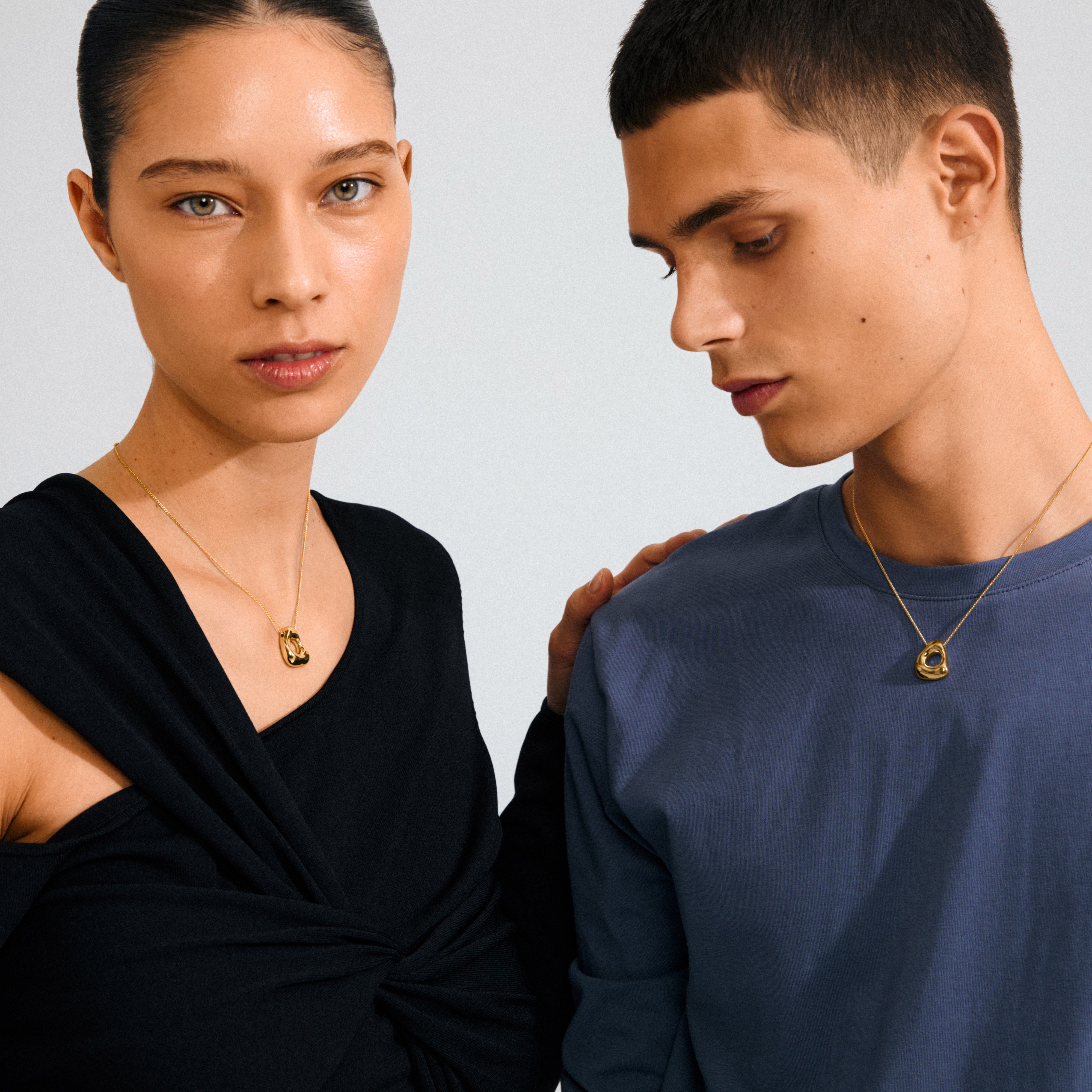 Two models wearing Pilgrim's FREE 168一分钟极速赛车--|实时赛果直播视频 gold-plated necklaces; the woman's draped top contrasts with the man's muted shirt, highlighting the delicate, nature-inspired pendants.