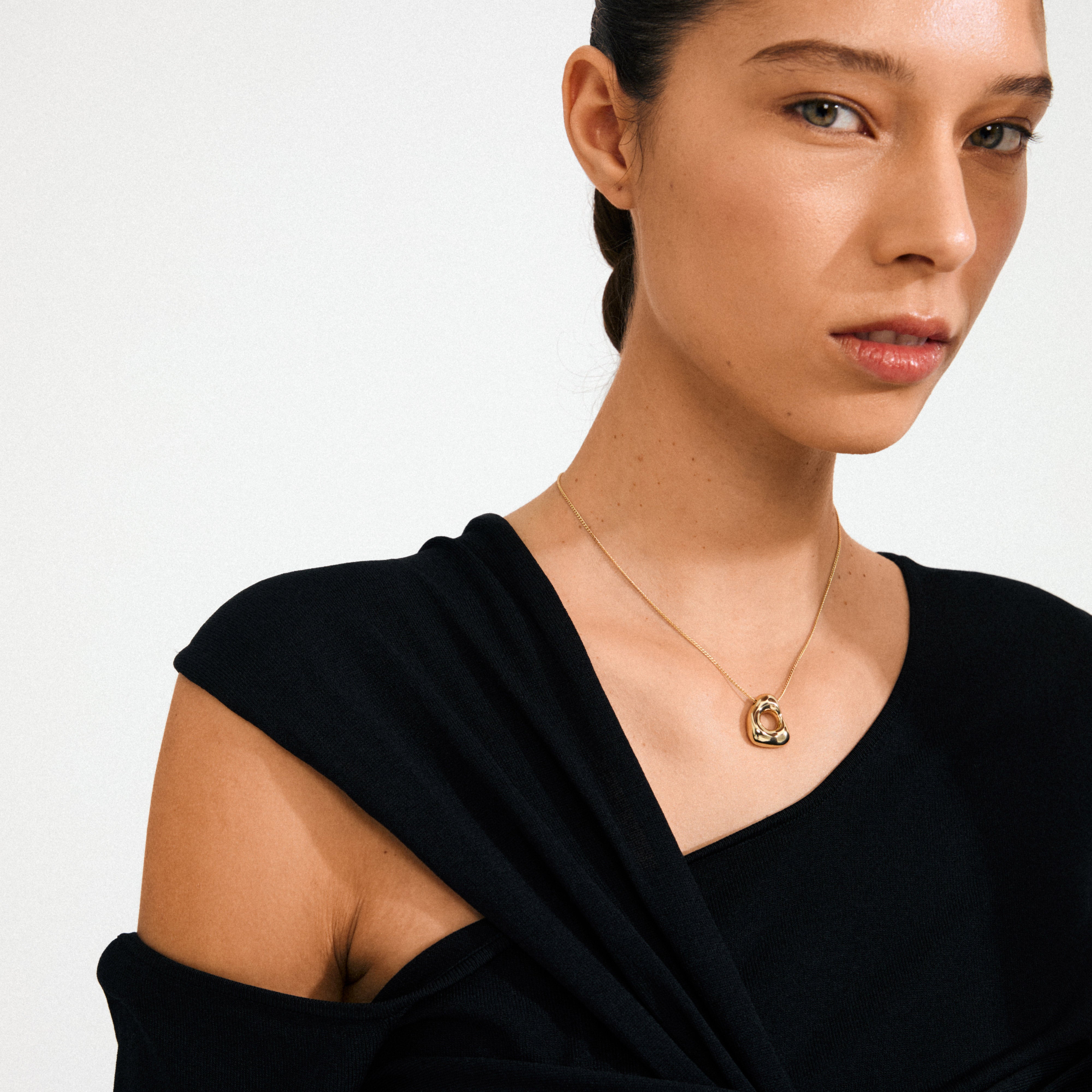 Young woman wearing Pilgrim's FREE necklace 168一分钟极速赛车--|实时赛果直播视频 gold-plated, featuring an interlocking circular pendant on a slender chain, embodying natural elegance and Scandinavian craftsmanship.