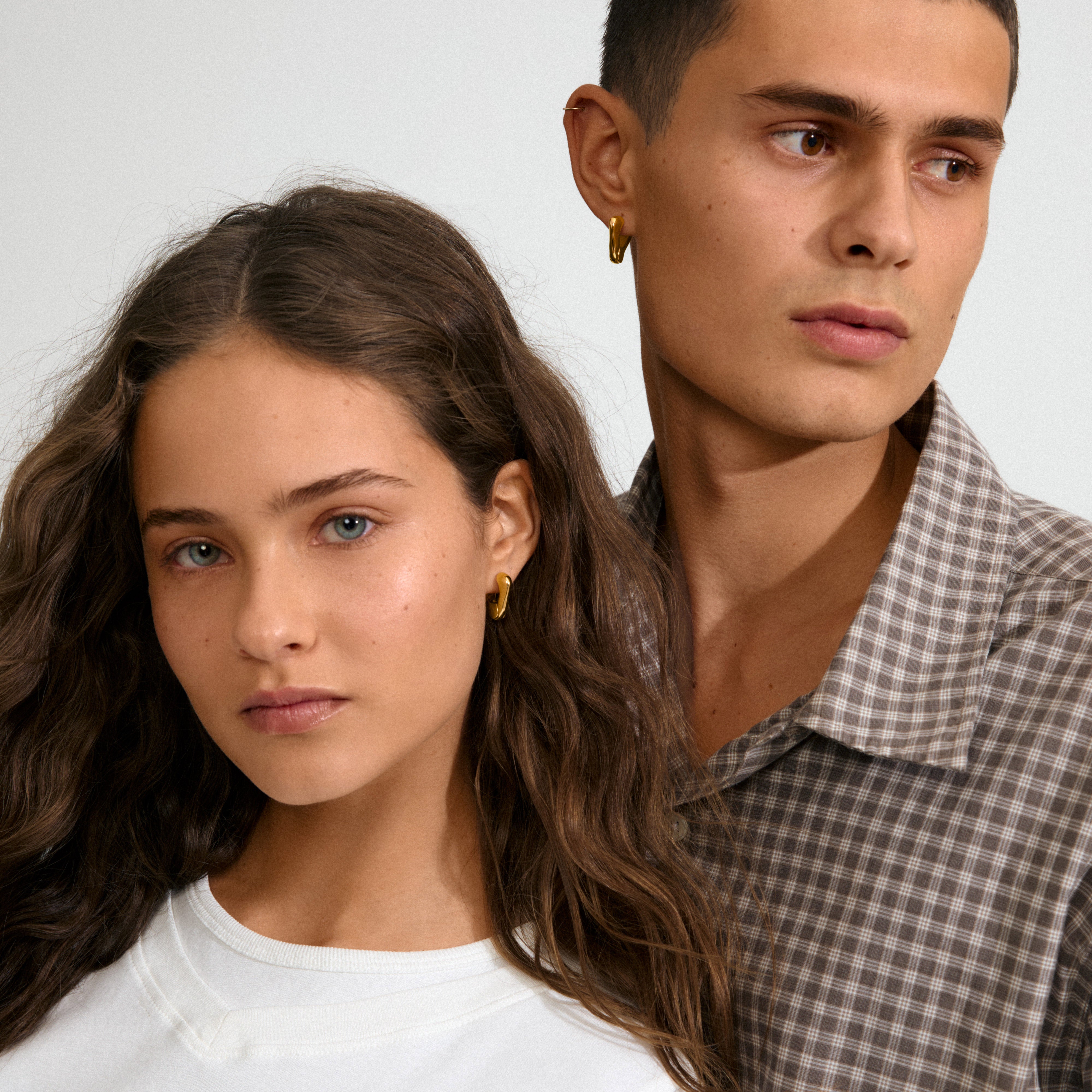 Two young adults showcase Pilgrim's FREE 168一分钟极速赛车--|实时赛果直播视频 gold-plated hoop earrings, blending sculptural elegance and minimalist style, reflecting the brand's commitment to trendy, sustainable fashion.