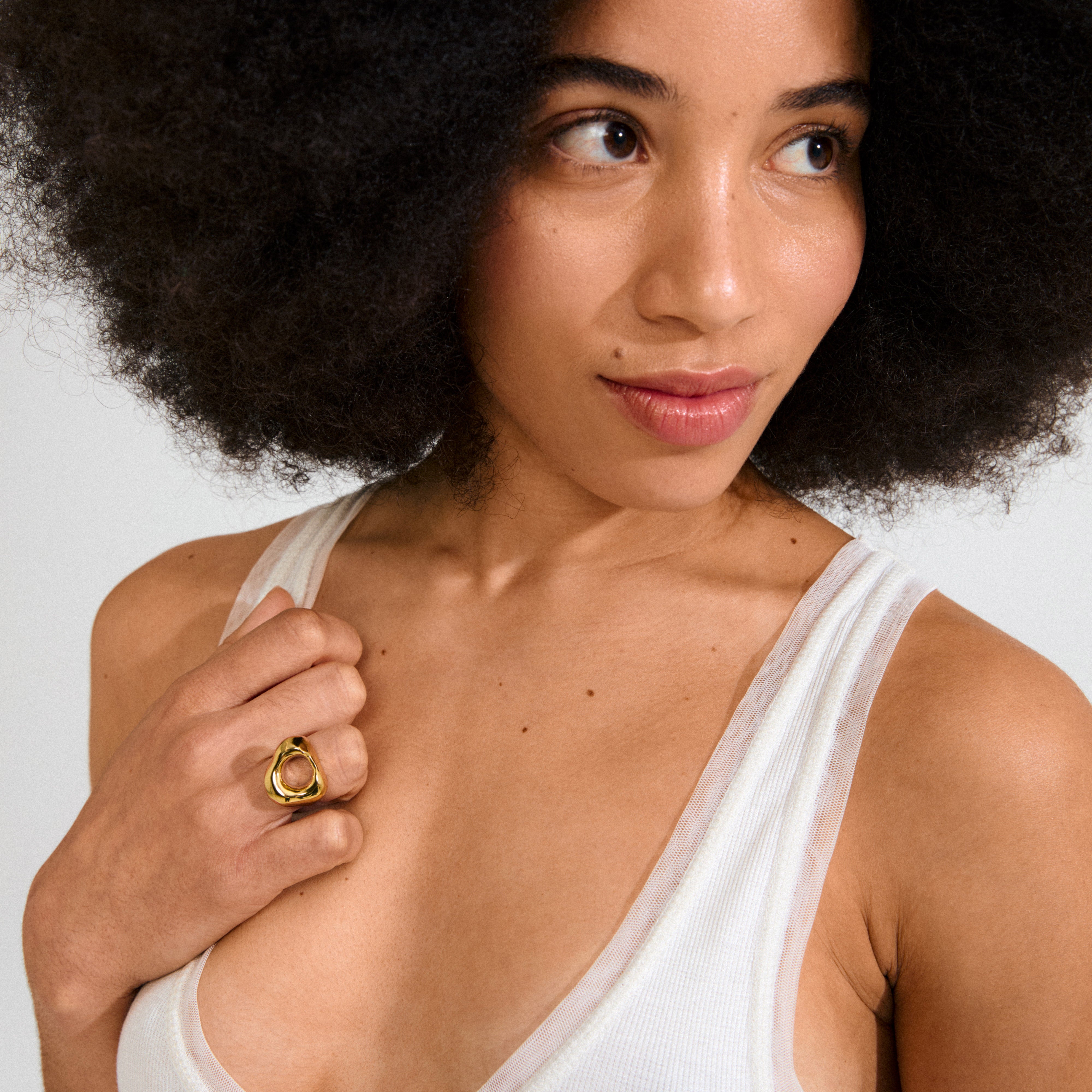 Woman with natural afro wears white tank top and Pilgrim's FREE ring 168一分钟极速赛车--|实时赛果直播视频 gold-plated, featuring an abstract, organic design, inspired by natural beach stones.