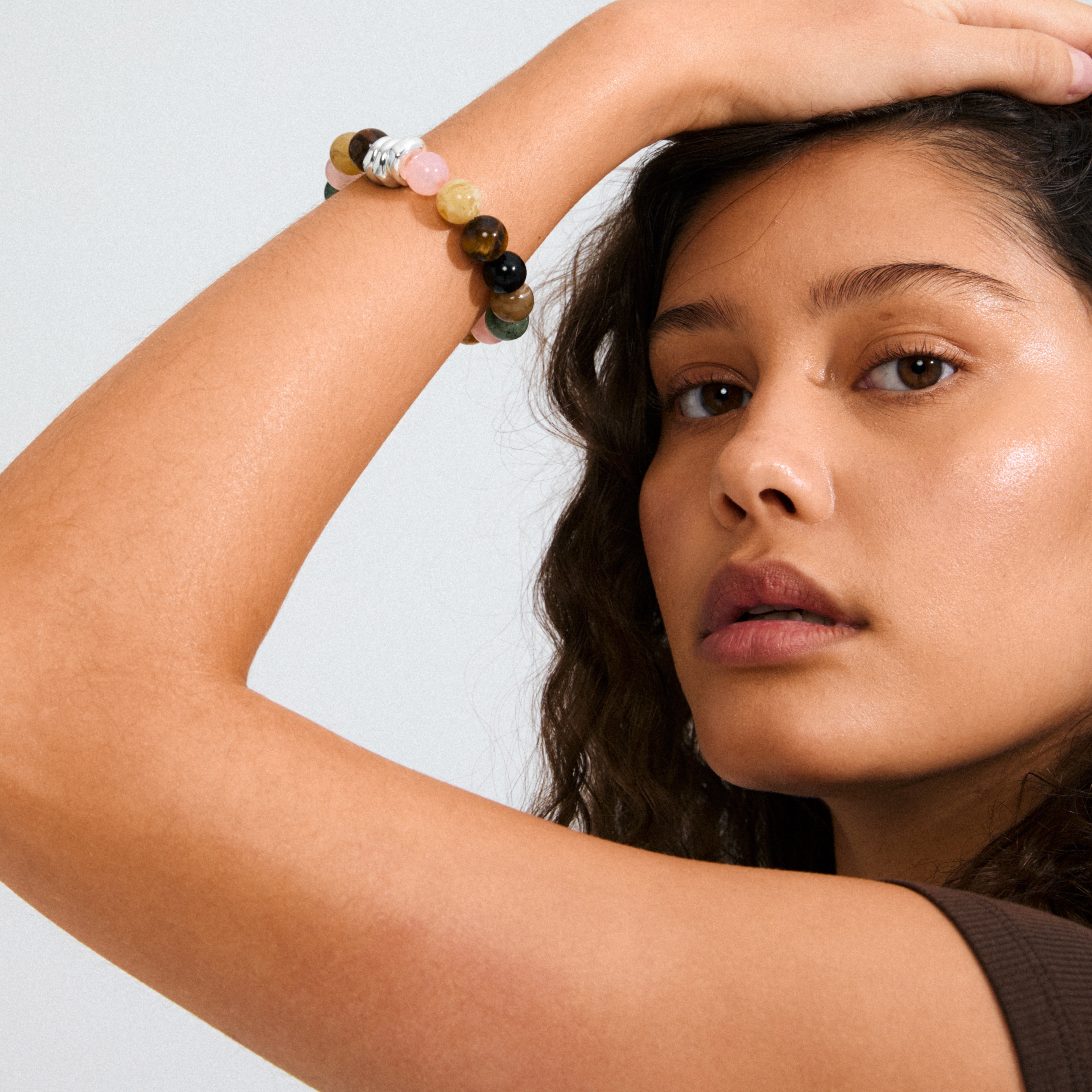 Young person wearing the UNFOLD bracelet from Pilgrim, featuring multi-colored beads and silver accents on a durable elastic, highlighting its stylish, earthy elegance.