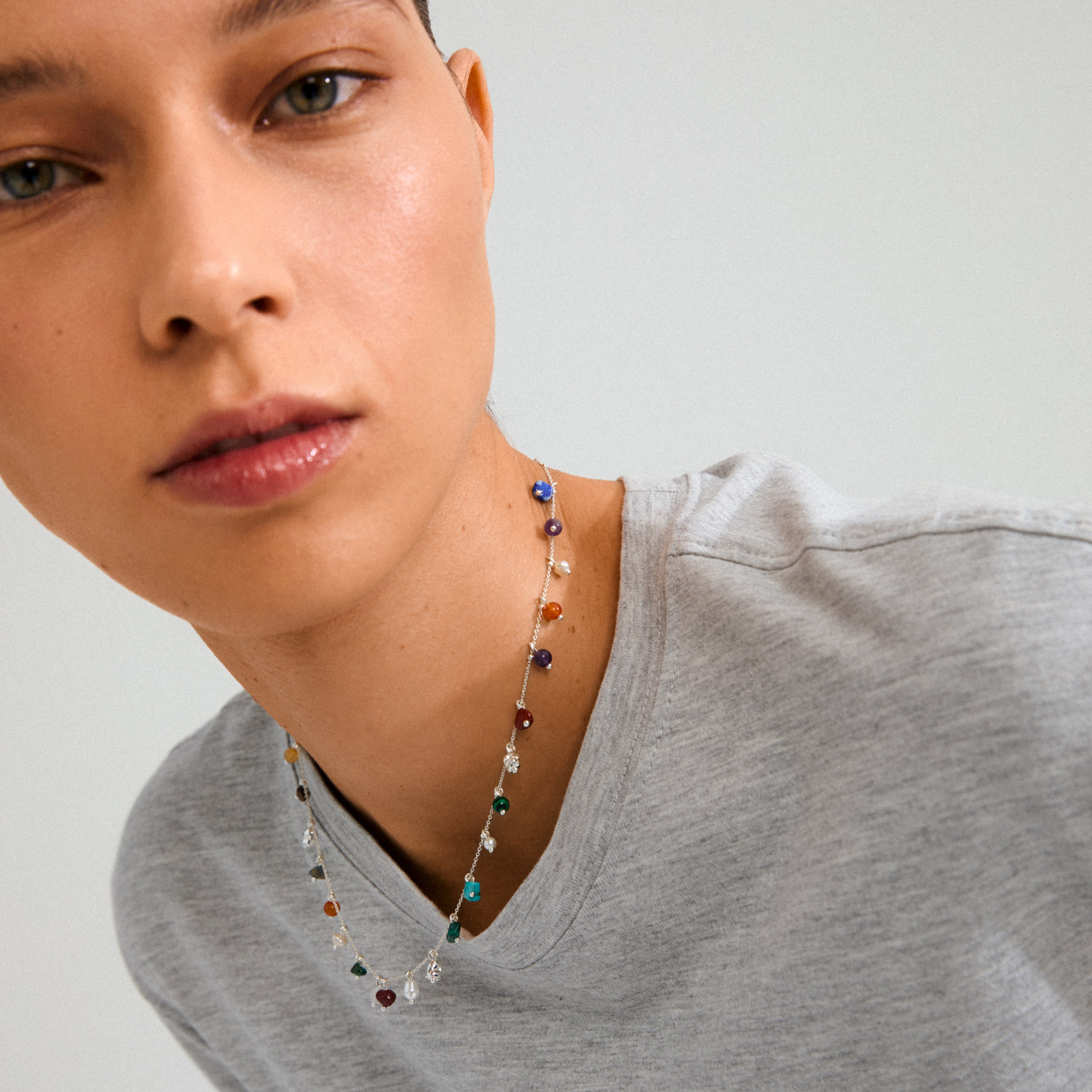 Close-up of a woman's face wearing the silver-plated BETWEEN necklace by Pilgrim, featuring vibrant semi-precious stones for a luxe boho style.